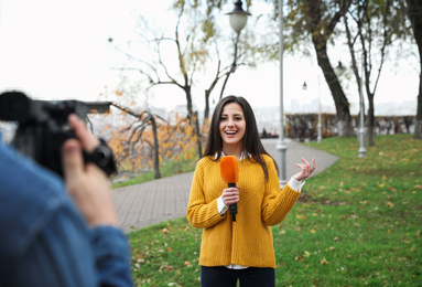 Young journalist and video operator working in park