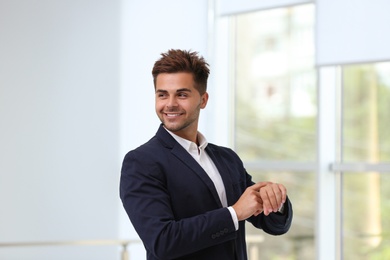 Photo of Portrait of handsome young man in elegant suit with wristwatch indoors