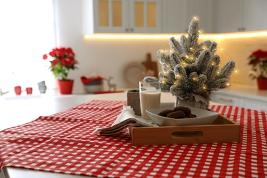 Tray with milk, cookies and small Christmas tree on table in kitchen. Interior design