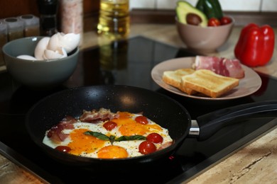 Tasty eggs with tomatoes and bacon in frying pan for breakfast