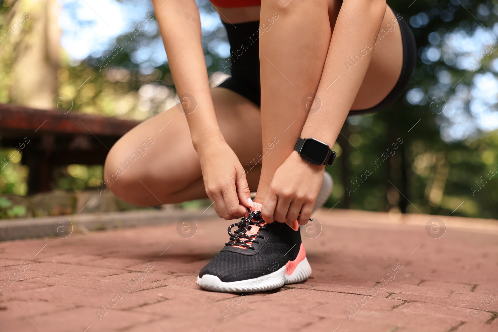 Photo of Woman in sportswear tying shoelaces in park, closeup