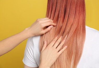 Woman with bright dyed hair on yellow background, back view
