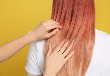 Photo of Woman with bright dyed hair on yellow background, back view