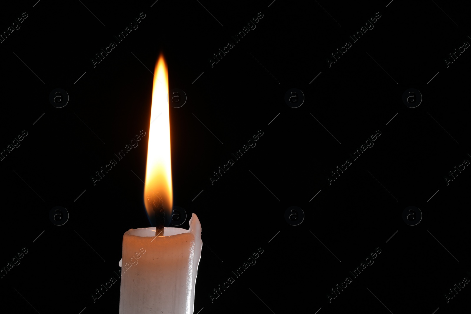 Photo of Burning candle on black background, closeup. Space for text