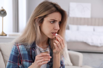 Photo of Upset young woman taking abortion pill at home
