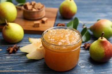 Photo of Tasty homemade pear jam and fresh fruits on blue wooden table