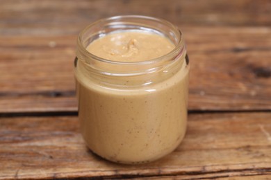 Tasty nut paste in jar on wooden table, closeup