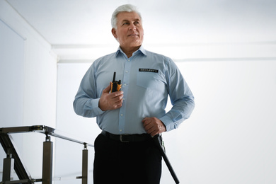 Photo of Professional security guard with portable radio set in office