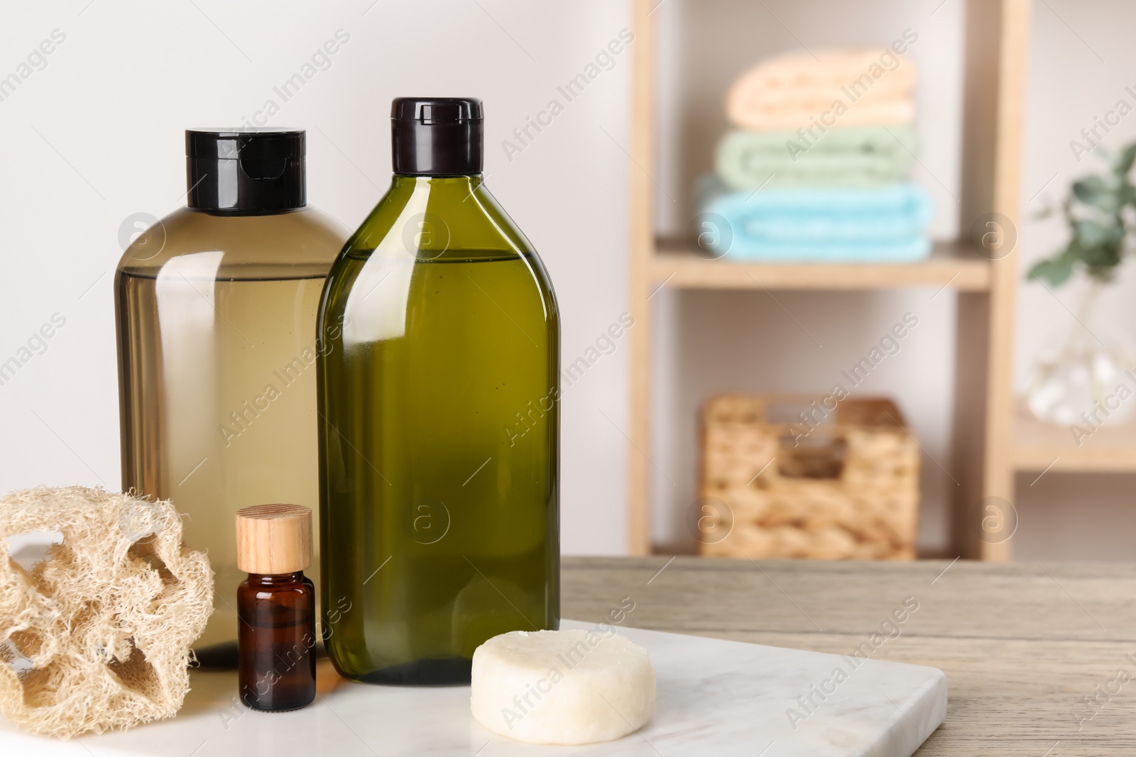 Photo of Solid shampoo bar and bottles of cosmetic product on wooden table in bathroom, space for text