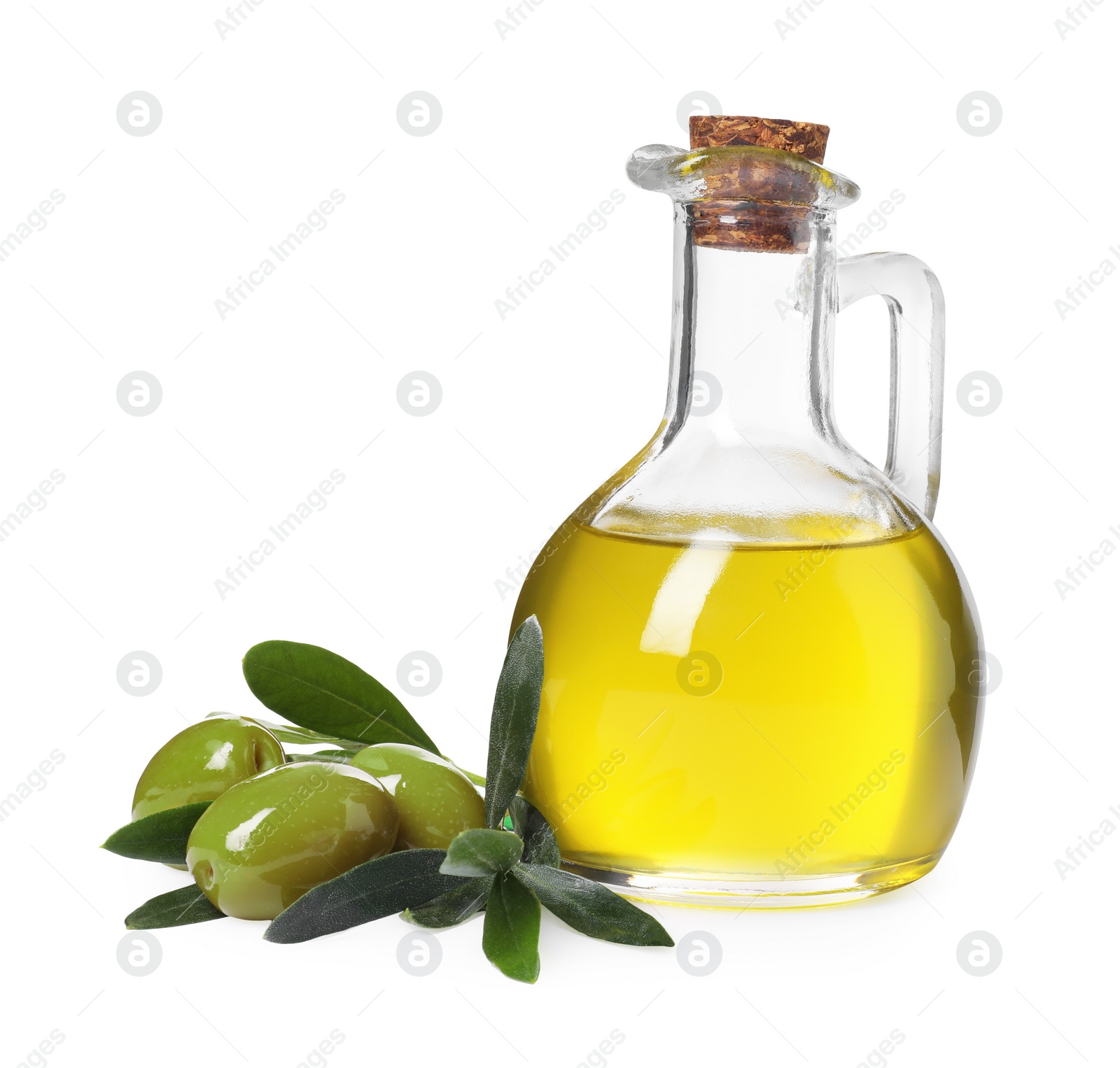 Photo of Glass jug of cooking oil, ripe olives and green leaves isolated on white