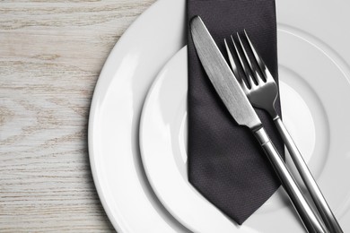 Photo of Business lunch concept. Plates, cutlery and tie on wooden table, flat lay