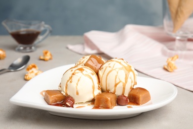 Delicious ice cream served with caramel and hazelnuts on table