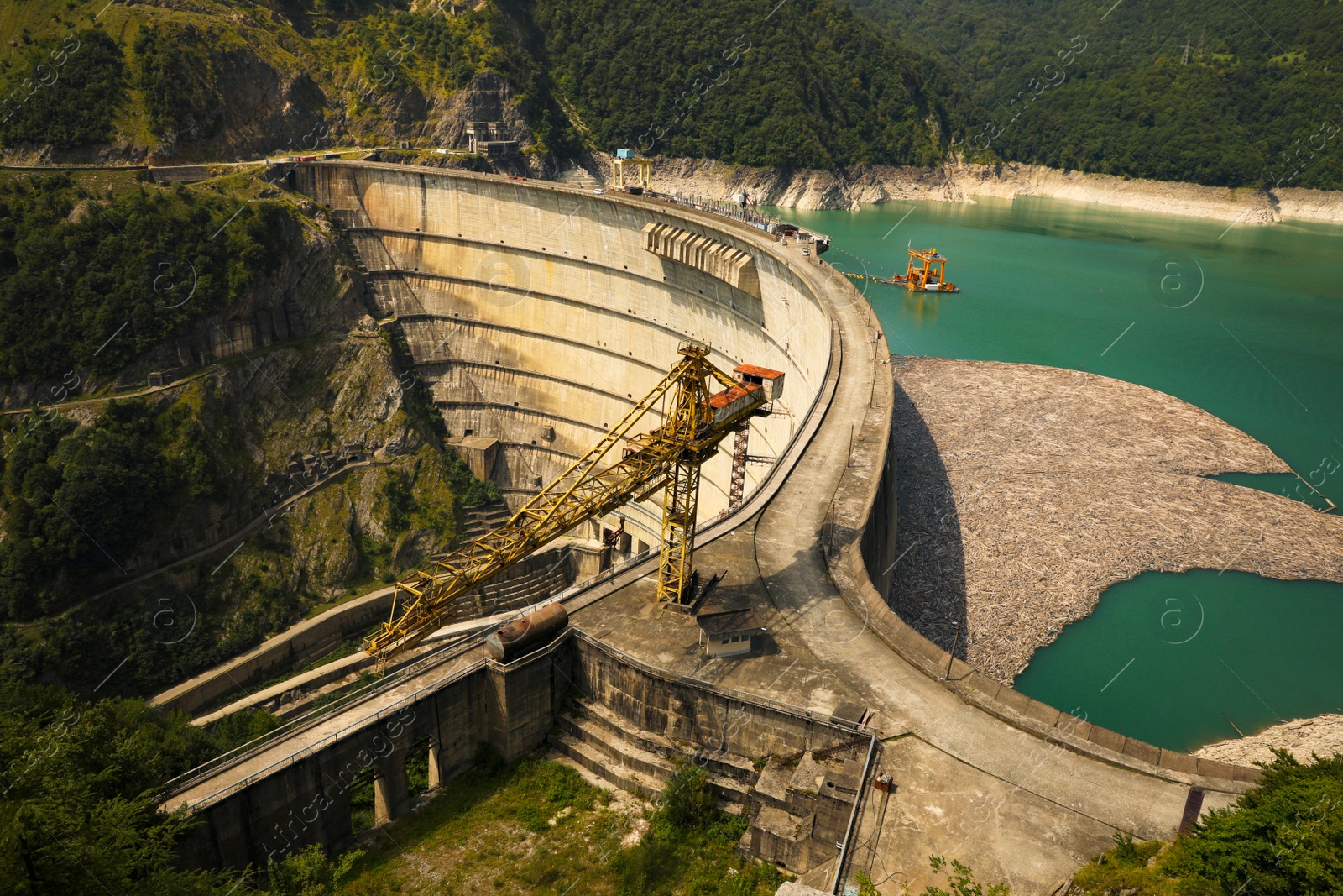 Photo of BATUMI, GEORGIA - AUGUST 13, 2022: Tower crane and hydroelectric power station in mountains