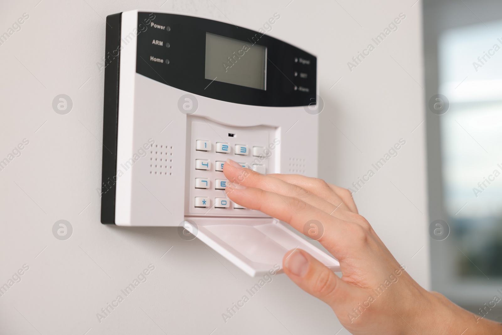 Photo of Woman entering code on home security system indoors, closeup