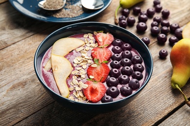 Photo of Bowl with tasty acai smoothie on wooden table