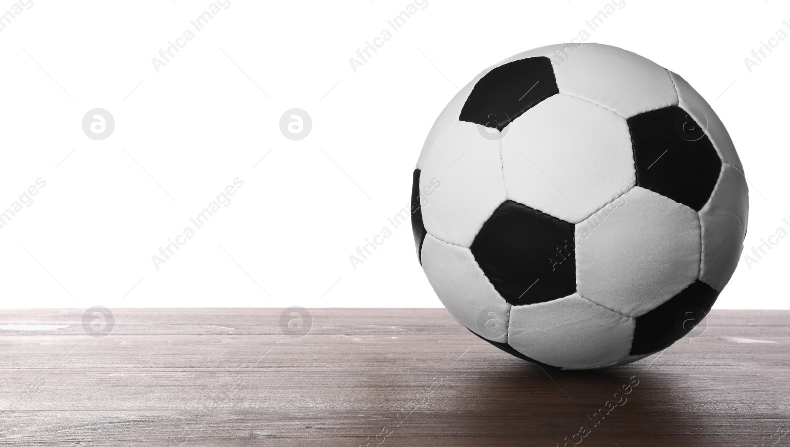 Photo of Football ball on wooden table against white background. Space for text