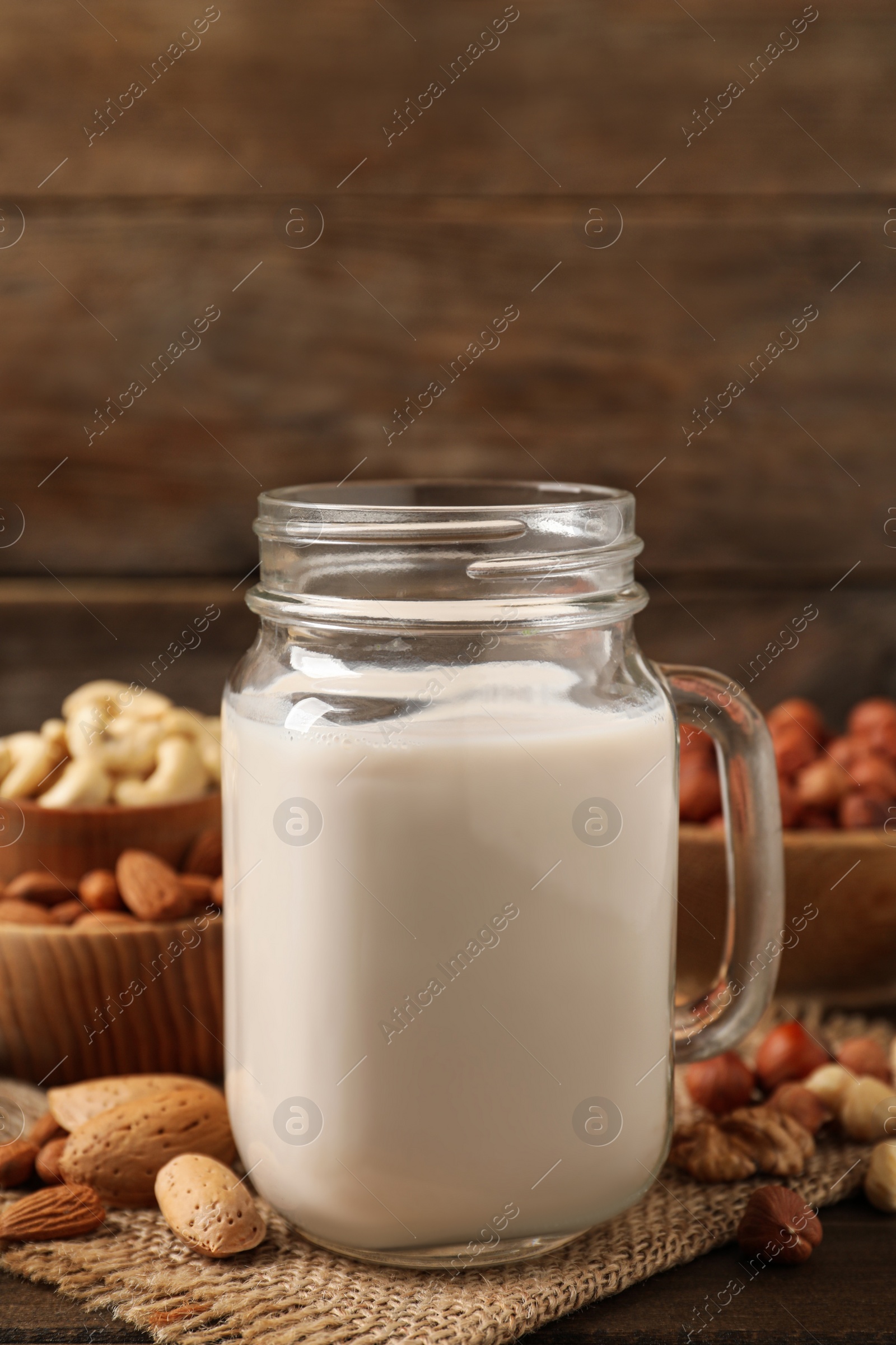 Photo of Vegan milk and different nuts on wooden table