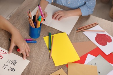 Photo of Children making beautiful greeting cards at table indoors, closeup