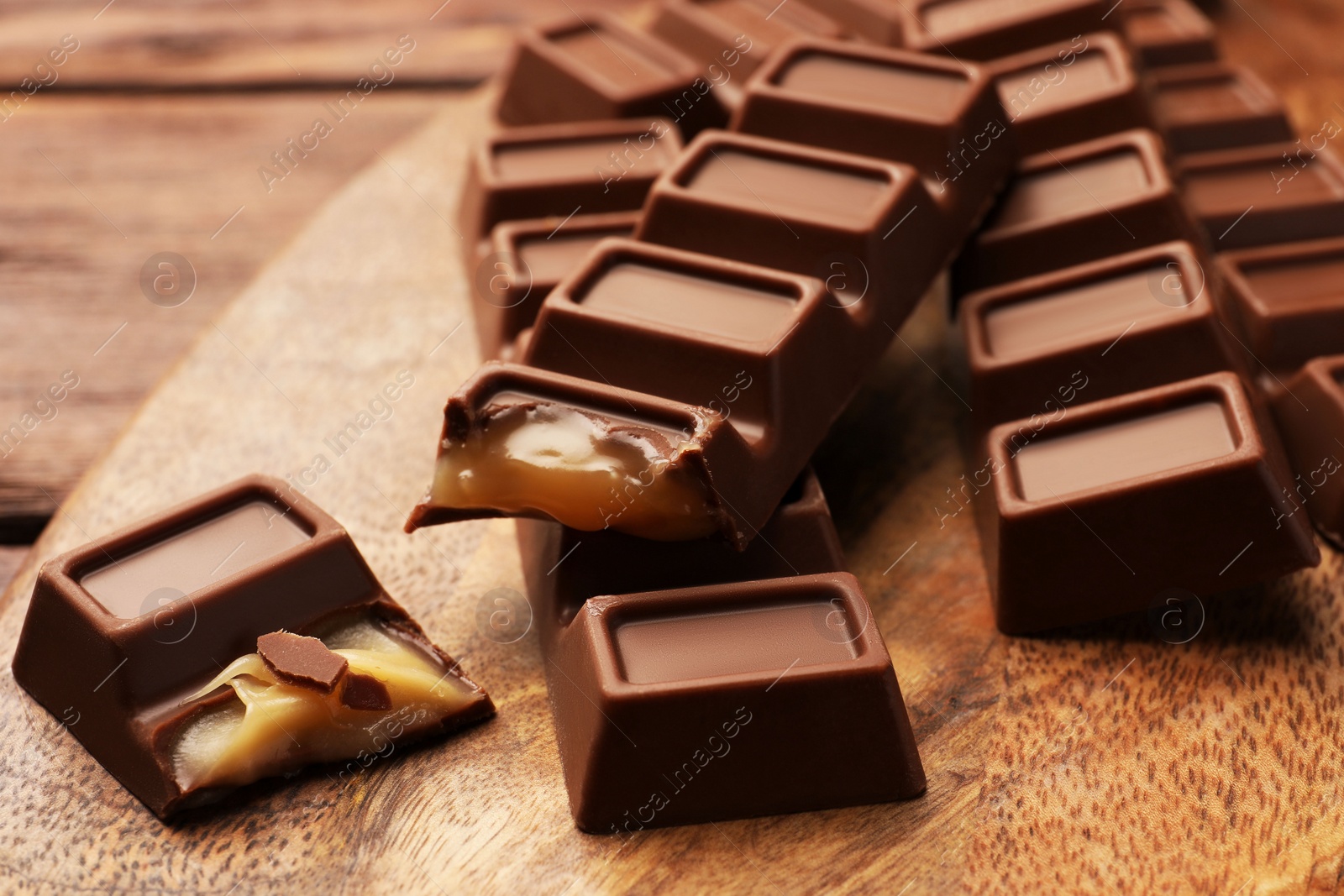 Photo of Tasty chocolate bars on wooden board, closeup
