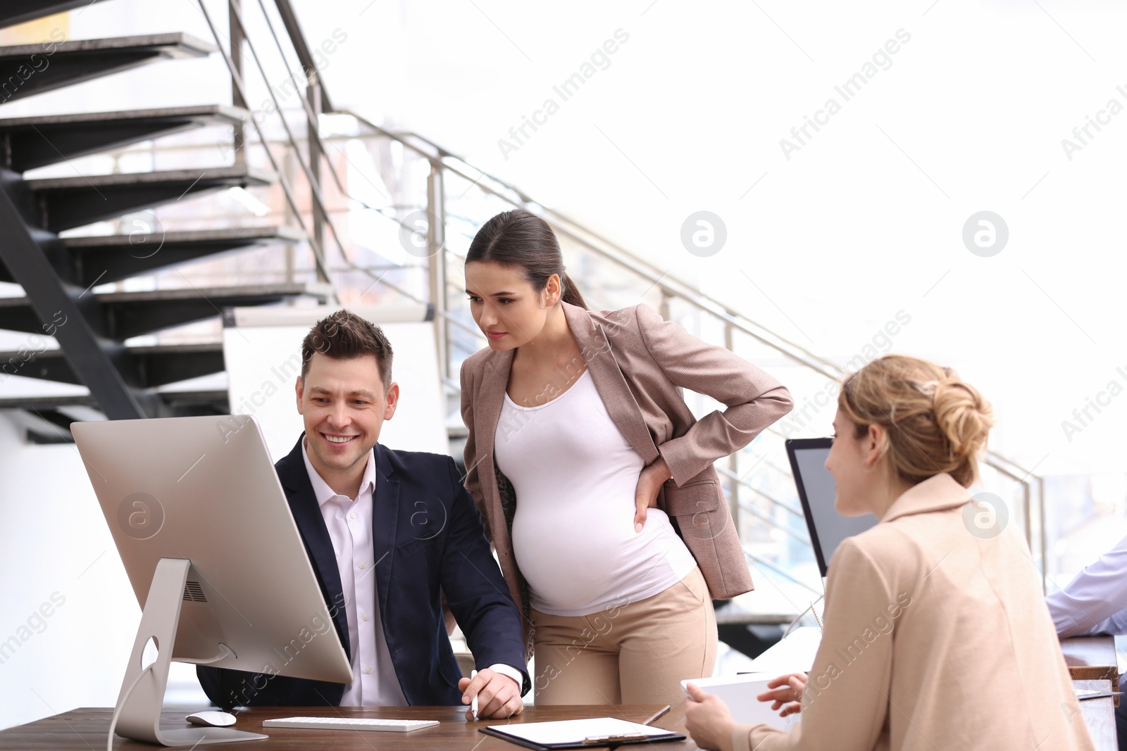 Photo of Young pregnant woman working with her employees in office