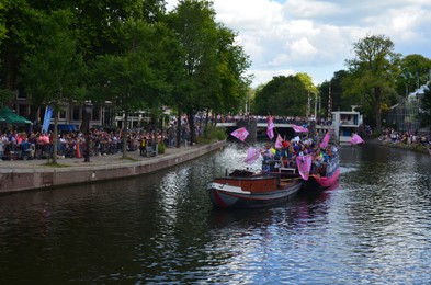 AMSTERDAM, NETHERLANDS - AUGUST 06, 2022: Many people in boats at LGBT pride parade on river