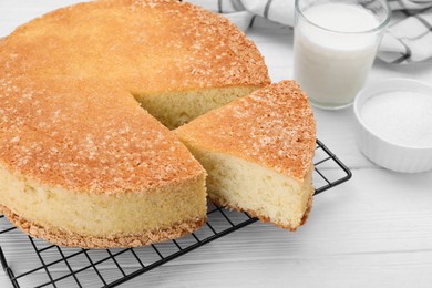 Tasty sponge cake on white wooden table, closeup