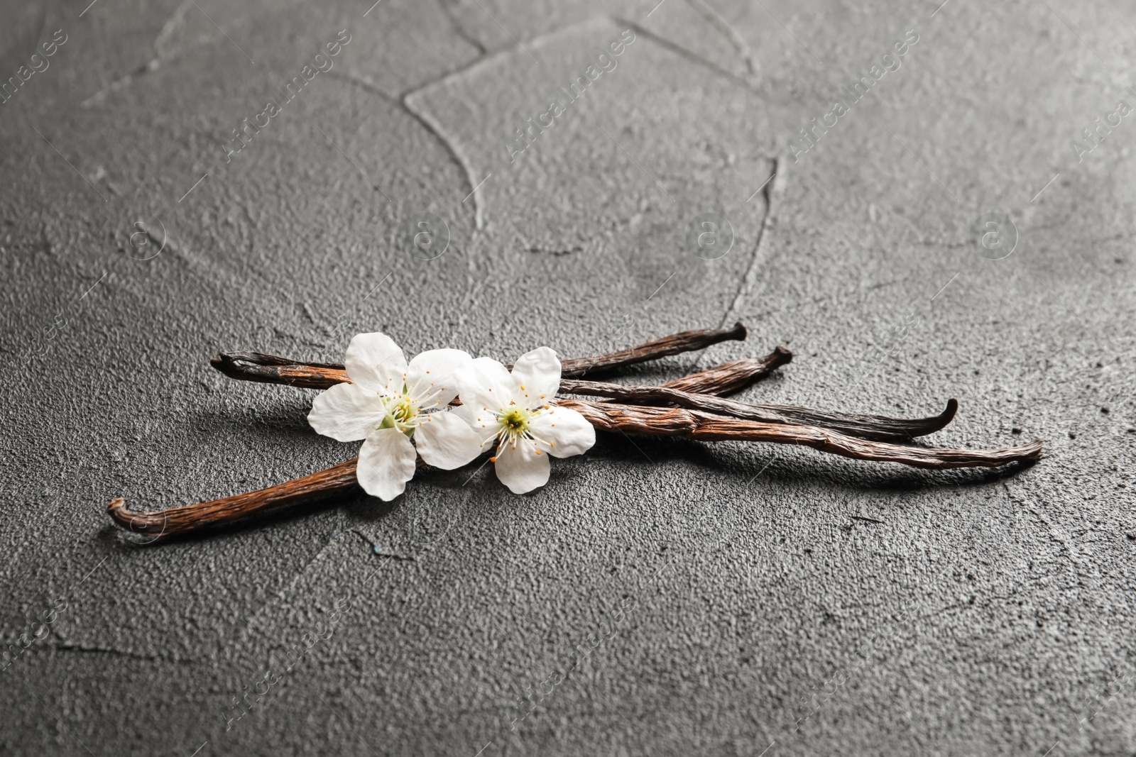 Photo of Vanilla sticks and flowers on grey background