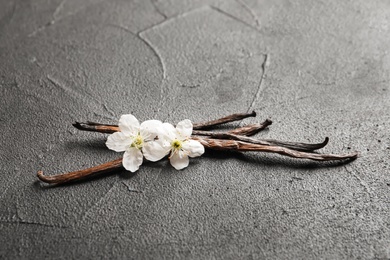 Photo of Vanilla sticks and flowers on grey background