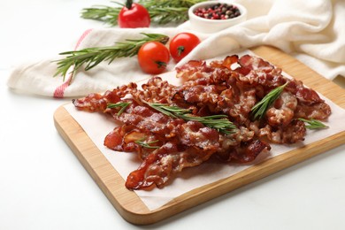 Photo of Slices of tasty fried bacon with rosemary on white table