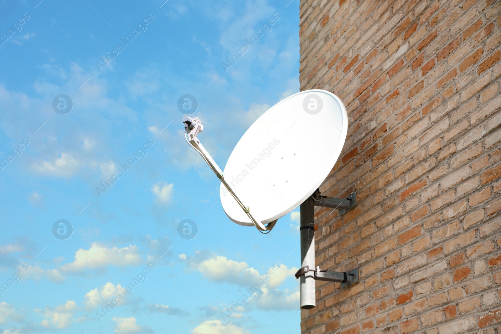 Photo of Satellite dish on brick wall of building against blue sky