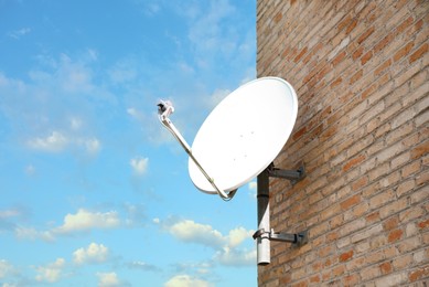 Photo of Satellite dish on brick wall of building against blue sky