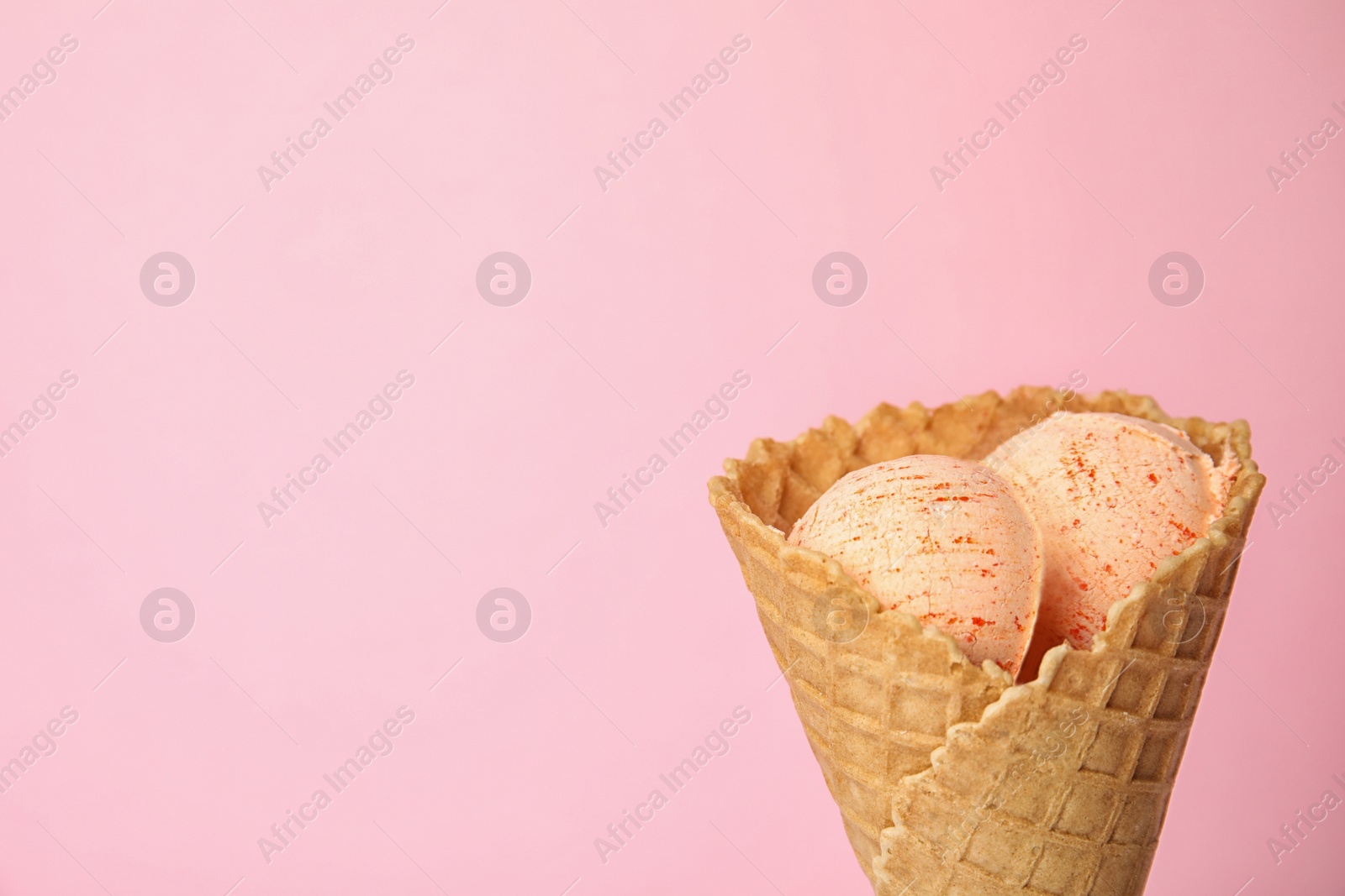 Photo of Delicious ice cream in waffle cone on color background, space for text