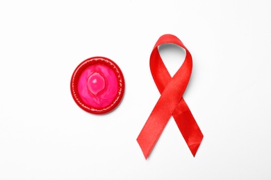 Photo of Condom and red ribbon on white background, top view. LGBT concept