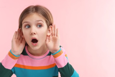 Photo of Little girl with hearing problem on pink background, space for text