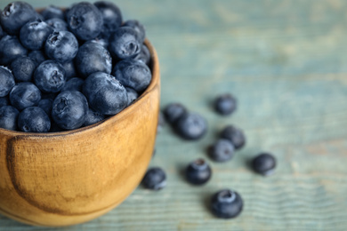 Fresh ripe blueberries in bowl on wooden table, closeup. Space for text