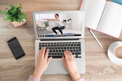 Image of Woman watching morning exercise video on laptop at table, top view