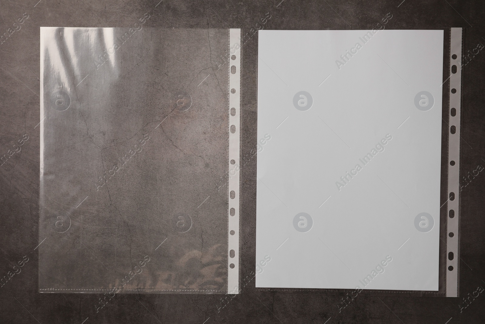 Photo of Punched pockets and paper sheet on grey table, top view. Space for text