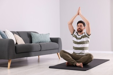 Photo of Man meditating at home, space for text