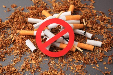 Photo of Prohibition sign, broken cigarettes and burnt matches on dark grey background, closeup. Quitting smoking concept