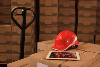 Image of Tablet and hardhat on boxes in warehouse. Wholesale business