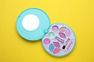 Photo of Decorative cosmetics for kids. Eye shadow palette with lipstick on yellow background, top view