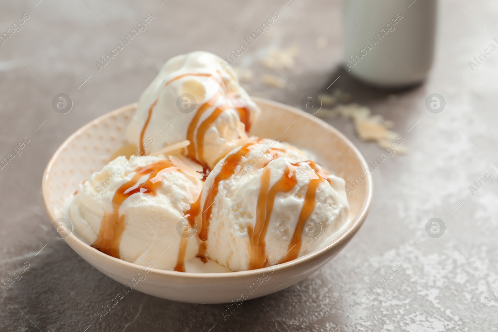 Photo of Tasty ice cream with caramel sauce in bowl on table