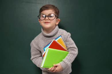 Photo of Cute little child wearing glasses near chalkboard. First time at school