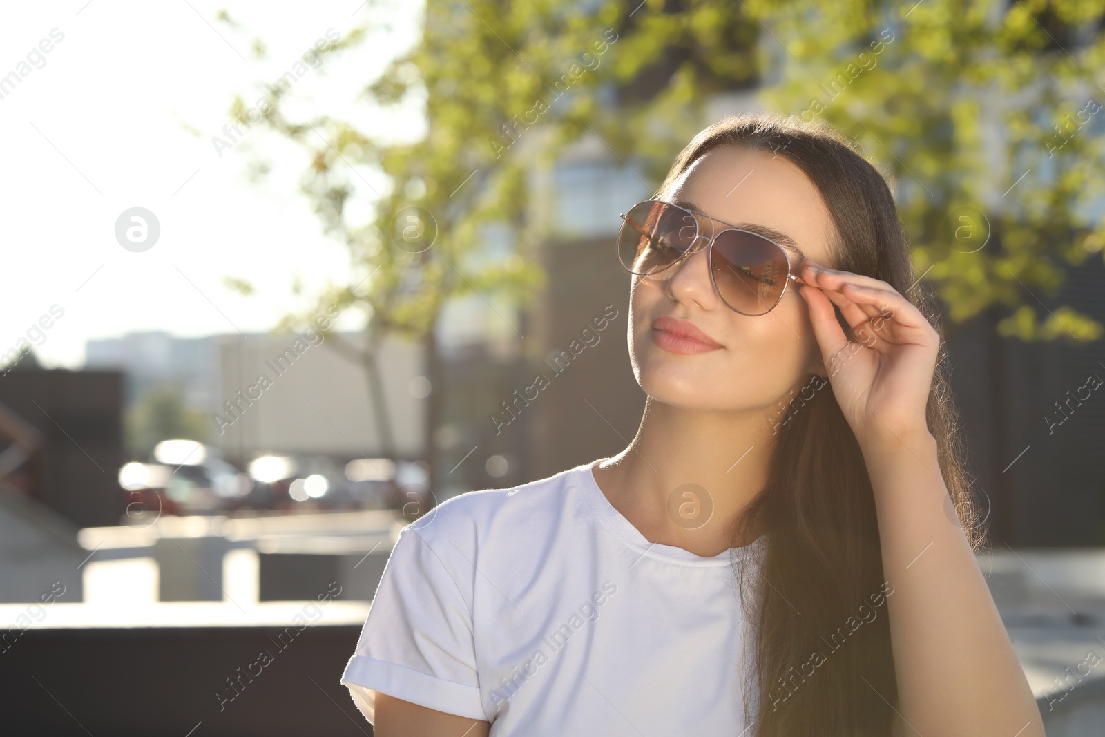 Photo of Beautiful woman in sunglasses on city street, space for text