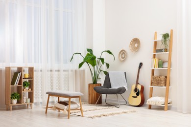 Photo of Spring atmosphere. Stylish room interior with comfortable chair, houseplant and shelving unit