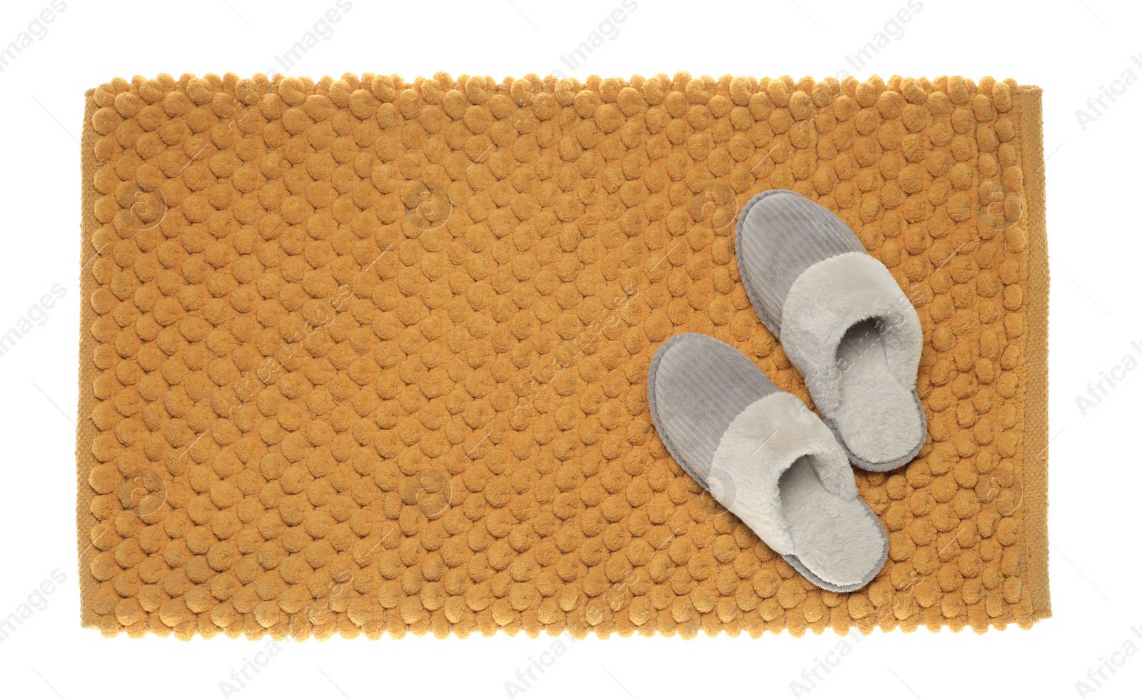Photo of Soft orange bath mat and slippers isolated on white, top view