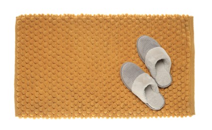 Photo of Soft orange bath mat and slippers isolated on white, top view