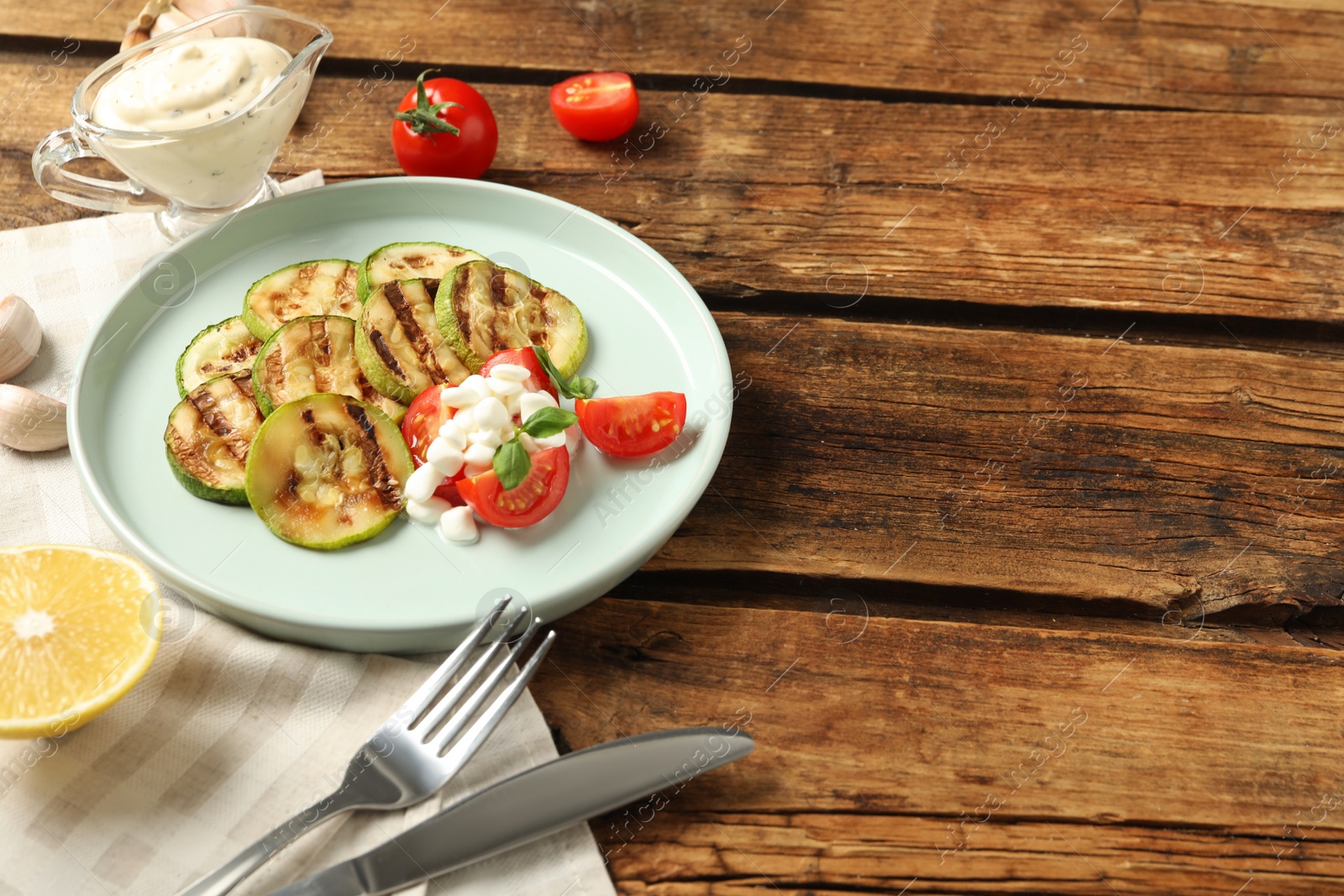 Photo of Composition with delicious grilled zucchini slices on wooden table, space for text