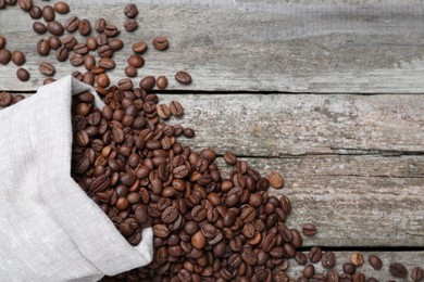 Photo of Bag with roasted coffee beans on wooden table, flat lay. Space for text