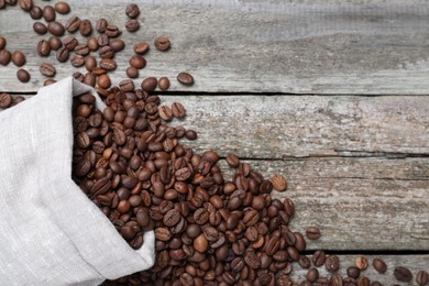 Bag with roasted coffee beans on wooden table, flat lay. Space for text